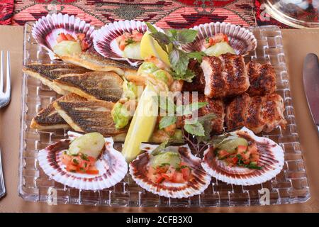 Platte mit gemischtem gegrilltem Fisch und Meeresfrüchten. (Seebarsch, Jakobsmuscheln, Garnelen und Hackfleisch Shish Kebab ) Stockfoto