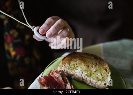 Nicht erkennbare ältere Frau mit faltiger Hand mit Anhänger mit Notfall Taste Stockfoto