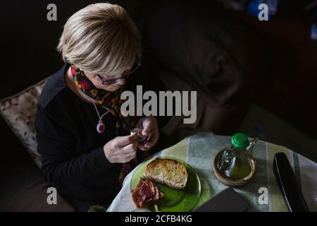 Ältere attraktive Frau, die vor dem Frühstück Medikamente aus der Pillenbox einnahm Stockfoto