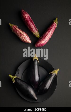 Set von frischen reifen Auberginen auf schwarzem Tisch platziert Stockfoto