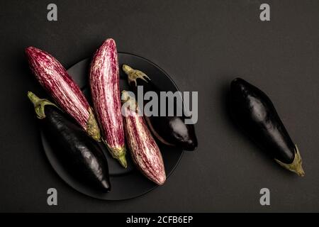 Set von frischen reifen Auberginen auf schwarzem Tisch platziert Stockfoto