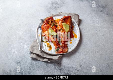 Gebackener Seebarsch serviert auf einem Teller mit Tomatensauce Und mit Petersilie und Zitrone dekoriert Stockfoto