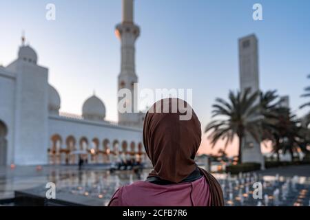 Frau in Hijab, die bei Sonnenuntergang eine Moschee anschaut Abu Dhabi Sheik Zayed Moschee Touristenattraktion Stockfoto