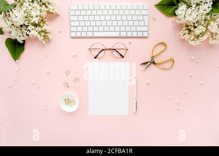 Arbeitsplatz mit Computer, Blumenstrauß Flieder, Zwischenablage. Damen Mode Accessoires isoliert auf rosa Hintergrund. Flach liegend. Schreibtisch mit Blick von oben. Stockfoto