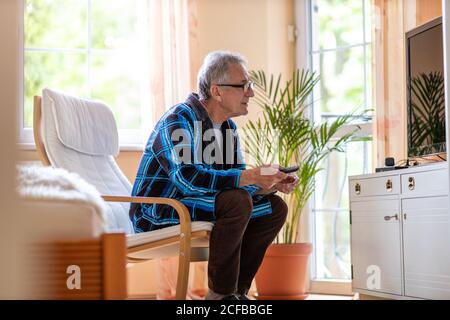 Älterer Mann mit TV-Fernbedienung Stockfoto