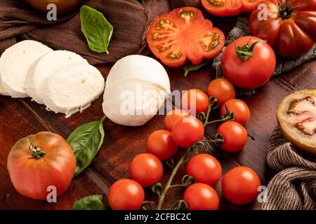 Frische Tomaten und Mozzarella Käse mit Basilikumblättern als Salat Platziert auf Holzbrett und Stoffserviette Stockfoto