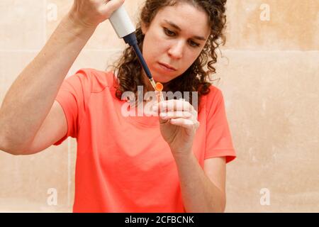 Junge Ärztin in orange Uniform Vorbereitung Impfstoff mit Spritze Gegen die Wand im modernen Krankenhaus Stockfoto