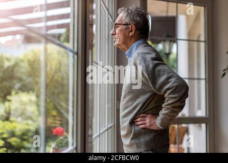 Ältere Menschen, die sich von Fenster zu Hause Stockfoto
