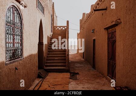 Außenansicht von alten traditionellen arabischen Häusern mit Treppe und Zierpflanzen fenster auf der schmalen Straße der Stadt in Marokko Stockfoto