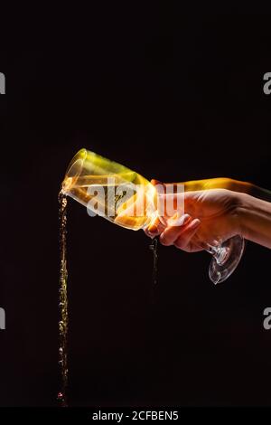 Anonymous Crop Person Gießen Alkohol aus Glas während der Party auf Schwarzer Hintergrund Stockfoto