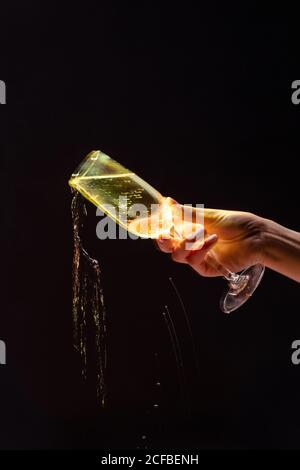 Anonymous Crop Person Gießen Alkohol aus Glas während der Party auf Schwarzer Hintergrund Stockfoto