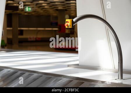 Roter Notausschalter über dem metallenen Gepäckförderband in Leeres Flughafenterminal Stockfoto