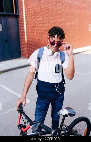Junger glücklicher afroamerikanischer Mann, der mit dem Fahrrad steht Stockfoto