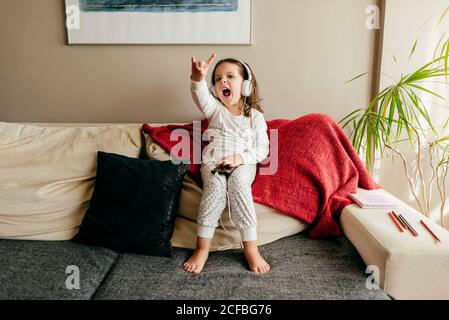 Süße kleine Mädchen sitzen auf der Couch Musik hören mit Kopfhörern Stockfoto