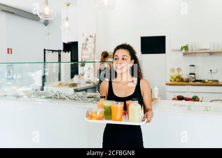 Fröhliche Kellnerin serviert gesunde Getränke für Freunde Stockfoto