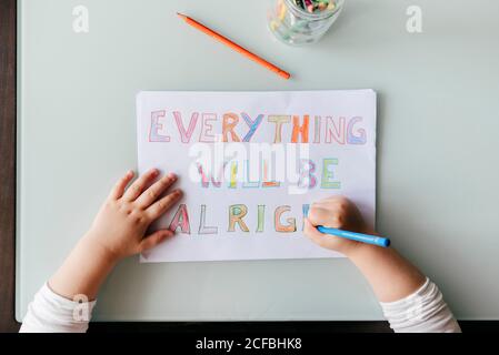 Kleines Mädchen in legerer Kleidung sitzt am Holztisch und Zeichnen Bild mit Buntstiften, während Sie Zeit zu Hause Stockfoto