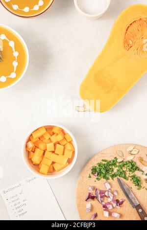 Kürbissuppe mit Kräutern, Sahne und Kürbiskernen auf weißem Hintergrund, Draufsicht, flach liegend. Stockfoto