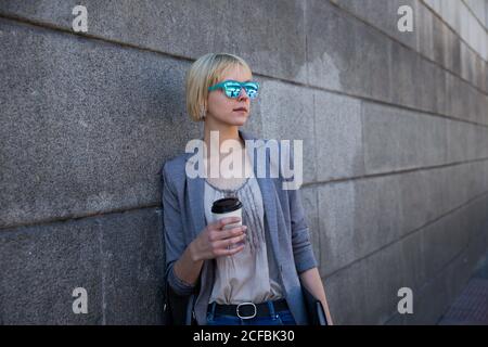 Geschäftsfrau mit Kaffee an der Wand Stockfoto