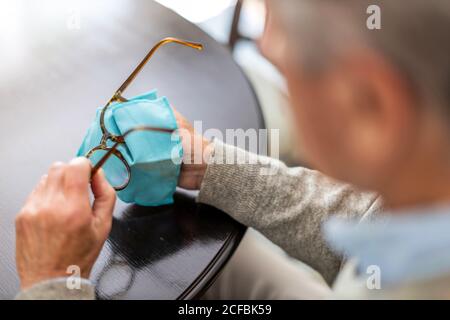 Älterer Mann, der Brillen mit Tuch abwischt Stockfoto