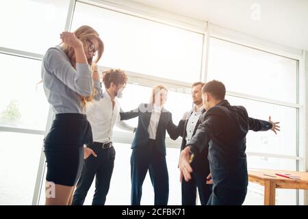 Fröhliche Geschäftsleute, die ihre Faust übereinander legen und lachen. Sie haben eine Schulung Stockfoto