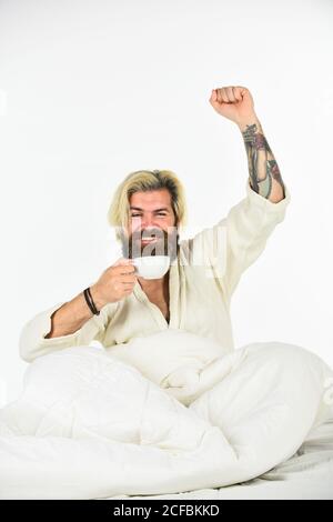 Schöner Mann trinkt Kaffee. Reifer bärtiger Mann im Bett. Start Tag mit gutem Kaffee. Gourmet-Espresso. Genießen Sie den morgendlichen Kaffee. Der Körper wurde von wesentlichen Komponenten für eine gute Gesundheit und Energie beraubt. Stockfoto