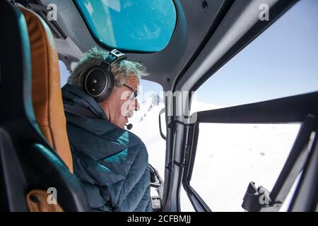 Hubschrauberpilot sucht nach einem Platz, um in schneebedeckten Bergen zu landen. Stockfoto