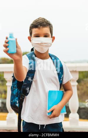 Student Junge mit Gesichtsmaske Anwendung Alkohol Handgel. Öffnen Sie die Schule wieder aus der Schließung. Zurück in die Schule: Covid-19 Coronavirus Pandemie. Neue normale Lebensdauer Stockfoto