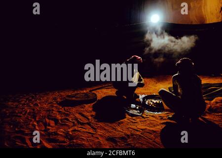 Zwei Beduinenmänner bereiten im Wadi Rum, Jordanien, ein traditionelles gekochtes Essen zu Stockfoto