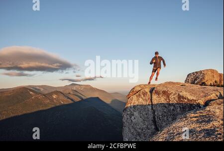Der Mensch läuft am Rand der Klippe auf dem Gipfel des Berges entlang Bei Sonnenuntergang in Maine Stockfoto