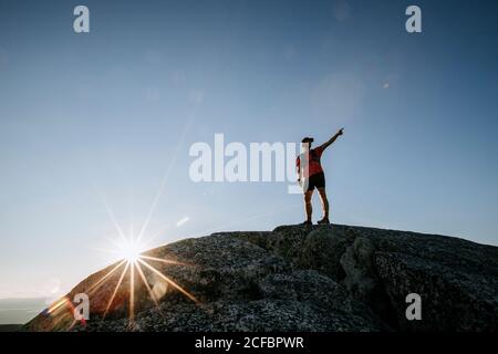 Männliche Wanderer zeigt auf Blick vom felsigen Gipfel des Berges Mit sunstar Stockfoto