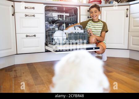 Kleiner Junge, der die Spülmaschine zu Hause beladen hat Stockfoto