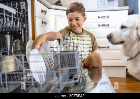 Kleiner Junge, der die Spülmaschine zu Hause beladen hat Stockfoto