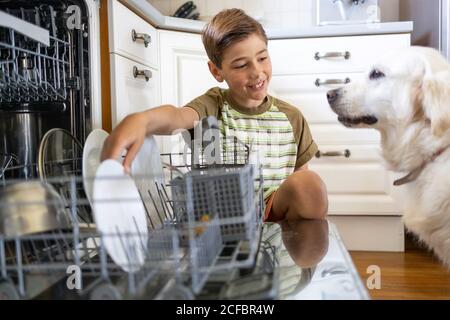 Kleiner Junge, der die Spülmaschine zu Hause beladen hat Stockfoto