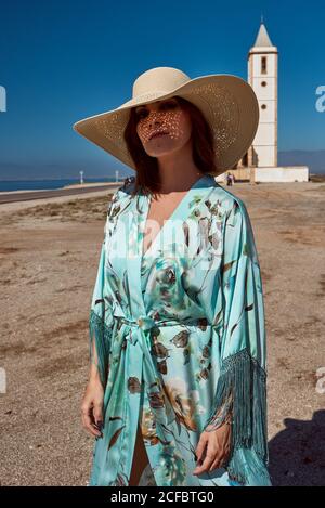 Eine Frau im Hut und blauem Kimono posiert mit einer Kirche im Hintergrund. Modekonzept Stockfoto