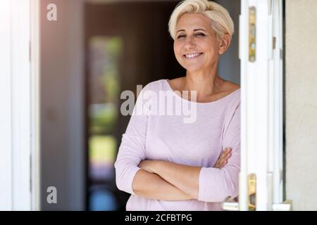 Lächelnde Frau, die in der Tür ihres Hauses steht Stockfoto