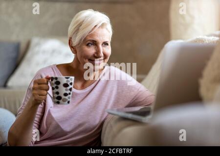 Reife Frau mit Laptop zu Hause Stockfoto