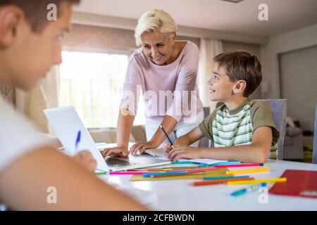 Mutter hilft ihren Kindern Hausaufgaben zu Hause Stockfoto