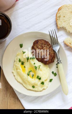 Schnittlauch, Kartoffelpüree mit Butter und Petersilie und Tee auf einem Holztisch. Stockfoto