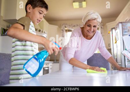Mutter und ihr Sohn putzen gemeinsam zu Hause Küchenoberfläche Stockfoto