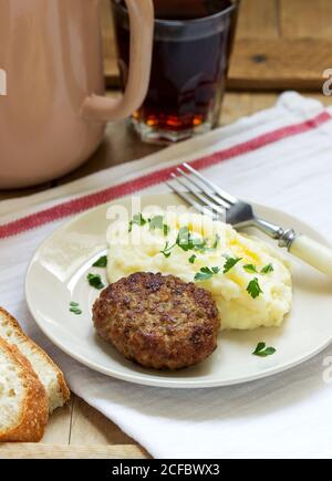 Schnittlauch, Kartoffelpüree mit Butter und Petersilie und Tee auf einem Holztisch. Stockfoto