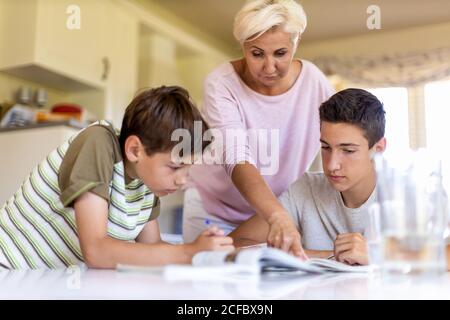 Mutter hilft ihren Kindern Hausaufgaben zu Hause Stockfoto
