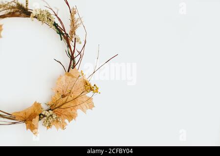 Handgefertigter rustikaler Herbstkranz an weißer Wand. Ländlicher Kranz aus Herbstblättern, Zweigen und Blumen. Hallo Herbst und Happy Thanksgiving Dekor Stockfoto