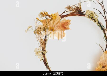 Handgefertigter rustikaler Herbstkranz an weißer Wand. Ländlicher Kranz aus Herbstblättern, Zweigen und Blumen. Hallo Herbst und Happy Thanksgiving Dekor Stockfoto
