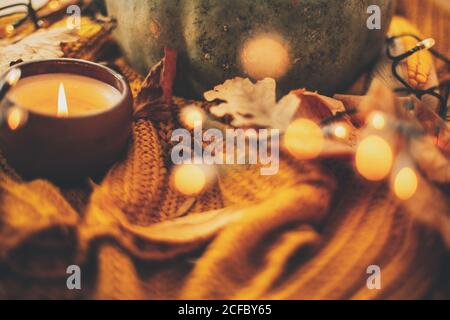 Happy Thanksgiving und Hallo Herbst, feiern Herbstferien in gemütlichen Hause. Herbstblätter, Gewürze und Kerze auf kuscheligem Strickpullover in warmem Gelb Stockfoto