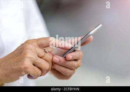 Die Hände einer älteren Frau halten ein Smartphone Stockfoto
