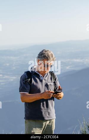 Älterer Mann, der sein Mobiltelefon auf dem Berg benutzt Stockfoto