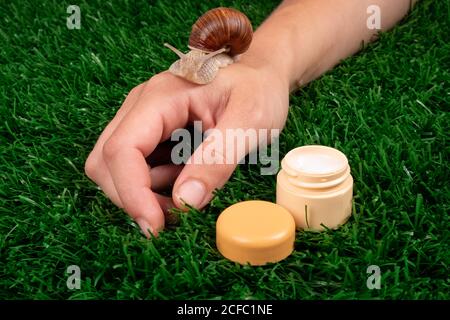 Schönheit, feuchtigkeitsspendende Handcreme mit Schneckenschleim, Hautpflege, Körperpflege Kosmetik auf grünem Gras. Stockfoto