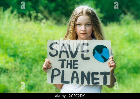 kaukasische blonde Mädchen Aktivist mit retten den Planeten Poster im Park. Preteen Kind Freiwilligen gegen Verschmutzung, globale Erwärmung, Müll zu recyceln. Ökologie Stockfoto