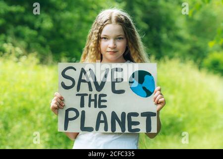 kaukasische blonde Mädchen Aktivist mit retten den Planeten Poster im Park. Preteen Kind Freiwilligen gegen Verschmutzung, globale Erwärmung, Müll zu recyceln. Ökologie Stockfoto