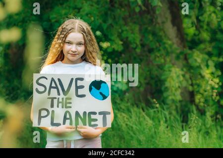 Kind Mädchen Aktivist mit retten den Planeten Poster im Waldpark. Preteen Kind Freiwilligen Kampf gegen Verschmutzung, Globale Erwärmung, Müll zu recyceln. Ecolog Stockfoto